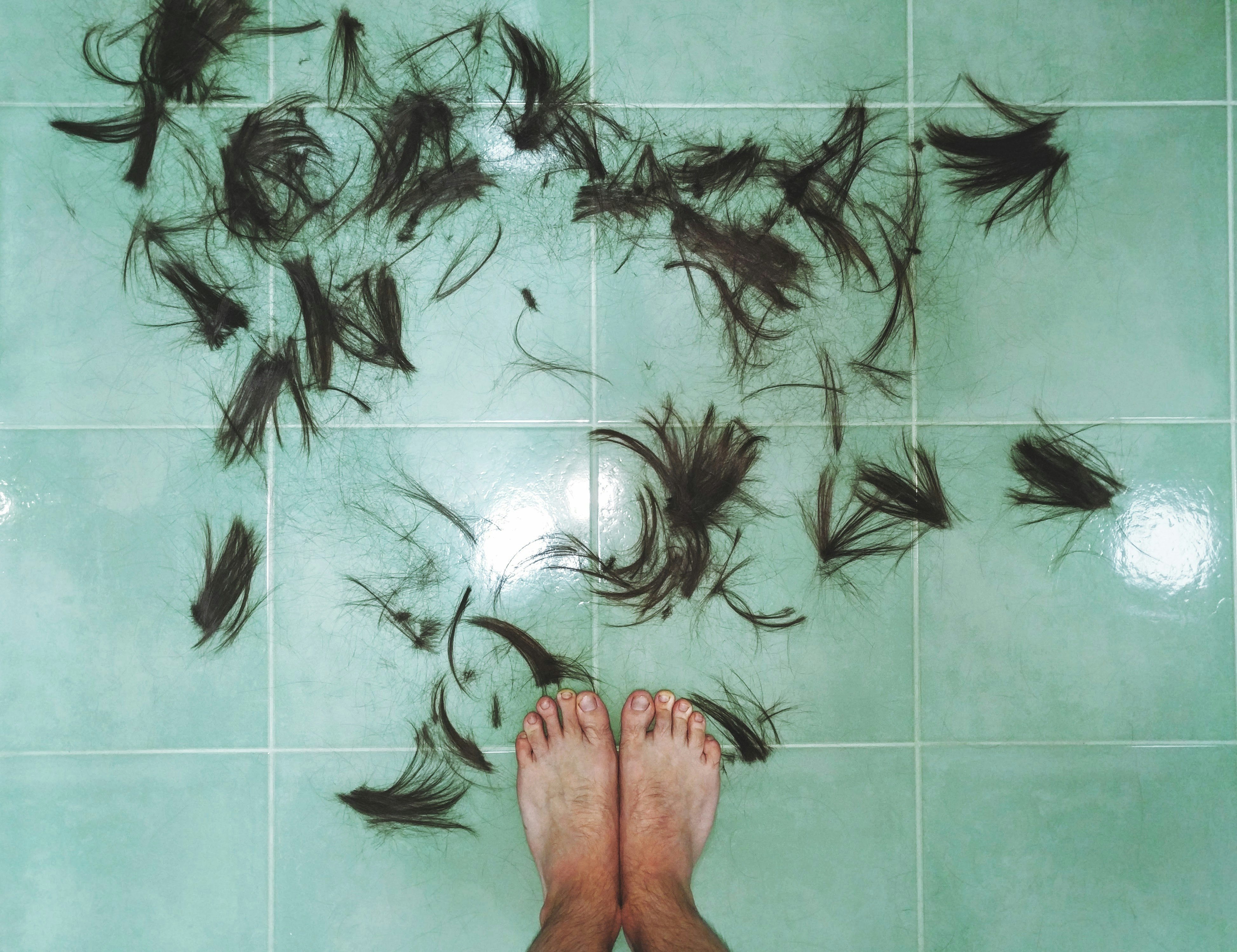 hair on tiled floor near person's feet